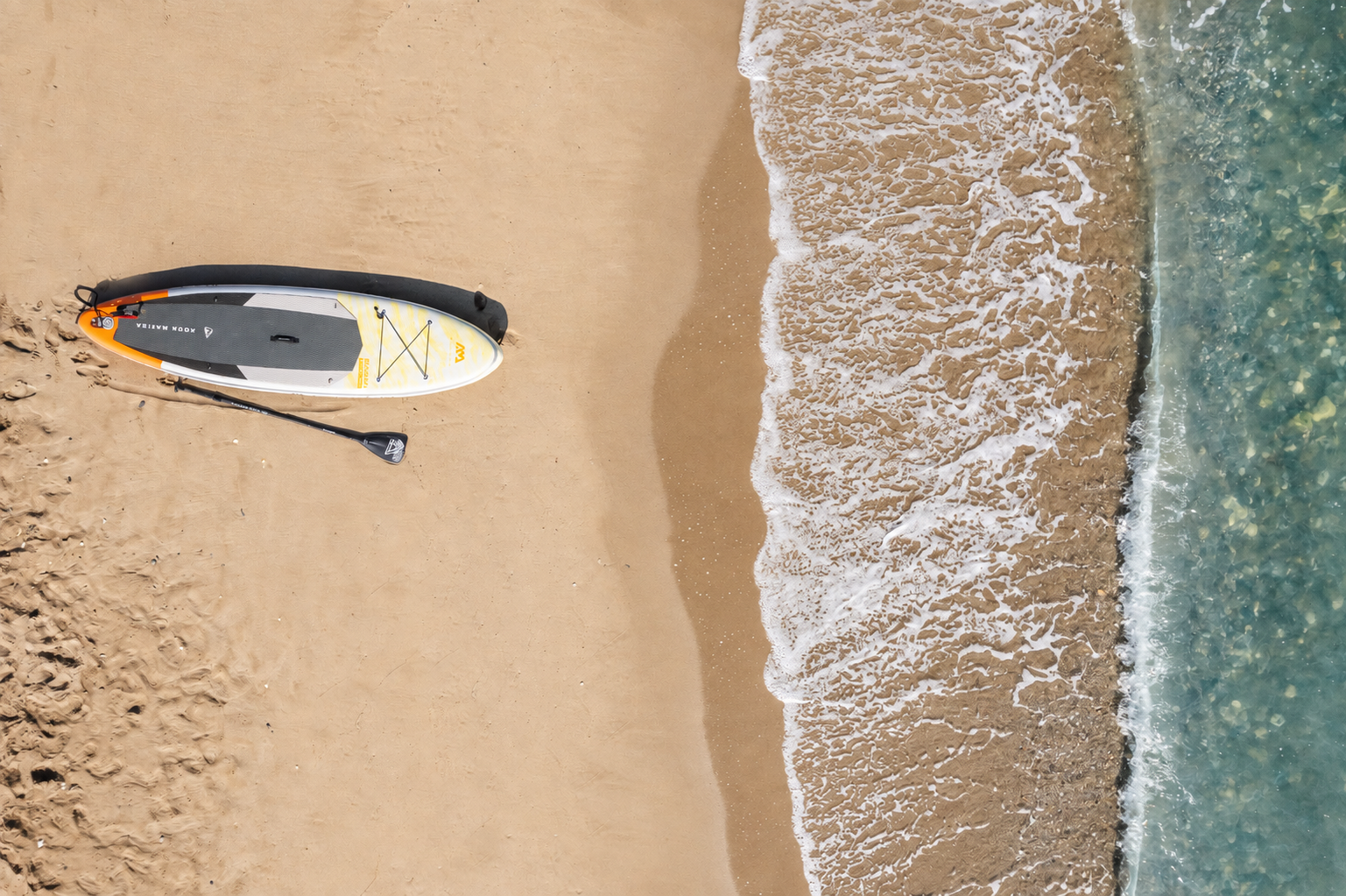 Paddleboard on the sand and clear water in front of Casa Negro