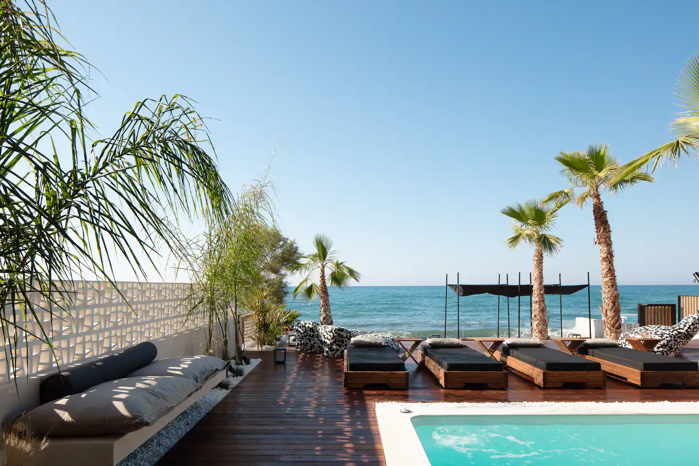 Pool terrace with daybeds and the Aegean beyond