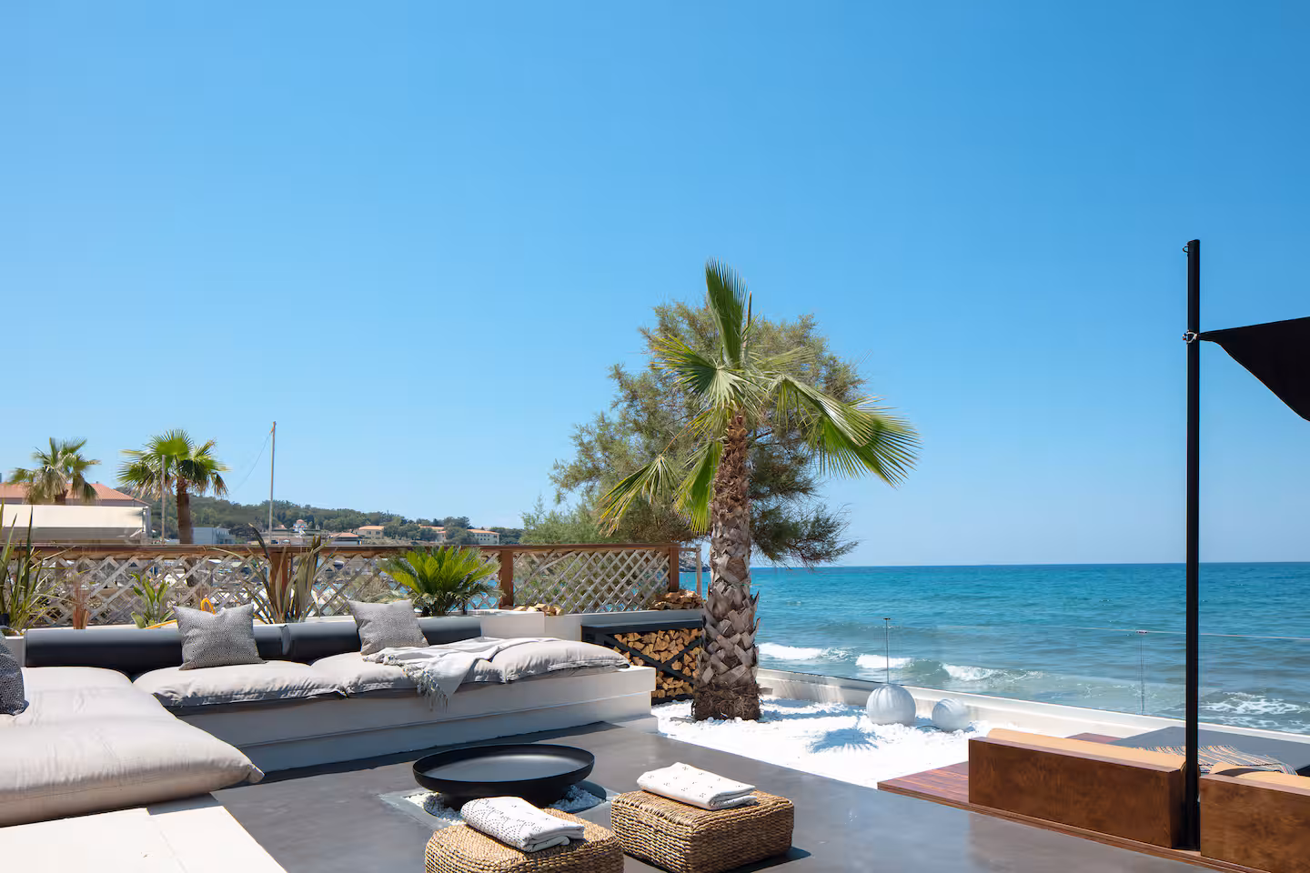 Outdoor lounge seating and poufs facing the sea