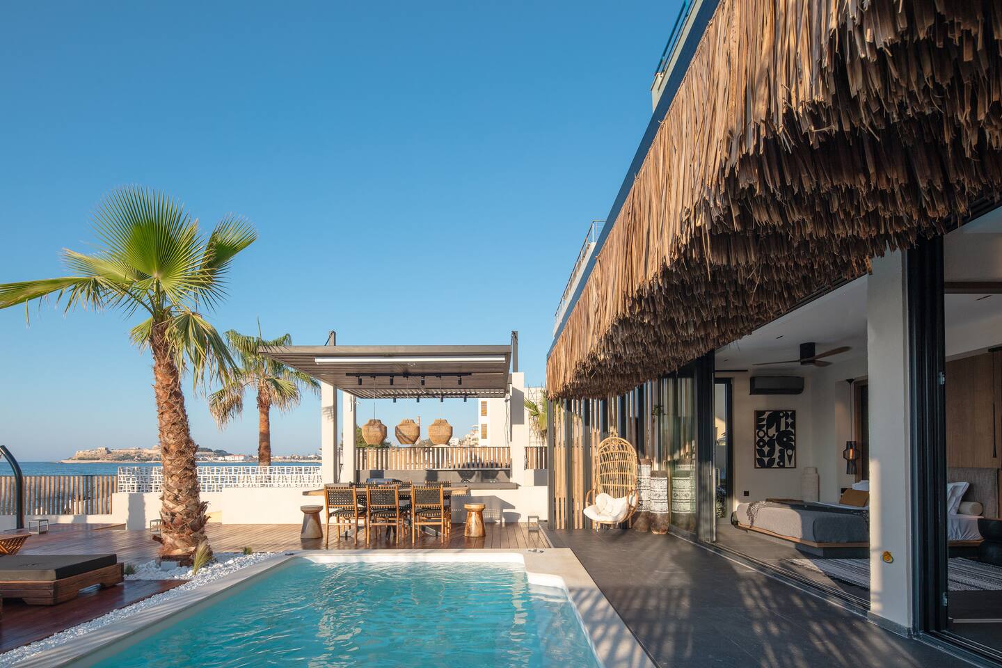 Pool, dining pergola and thatched terrace facing the sea